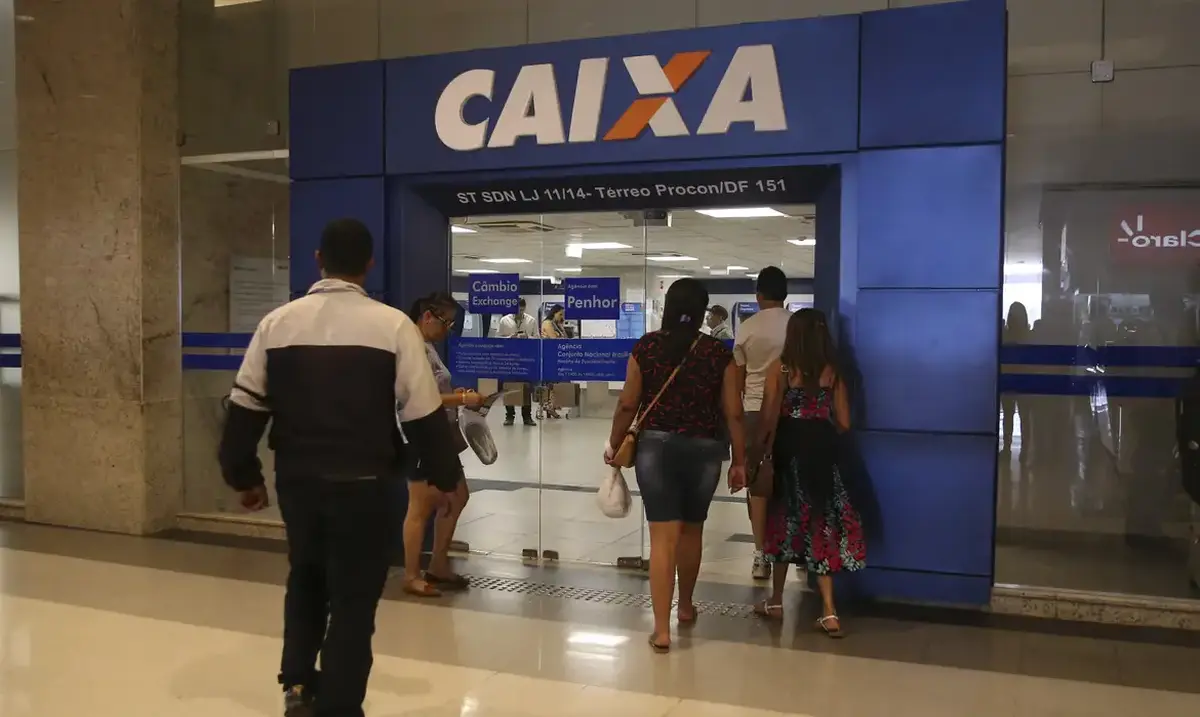 Agência da Caixa Econômica Federal com clientes entrando no local, em busca de atendimento.