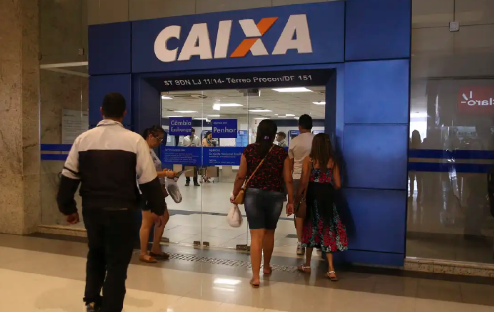Entrada de agência da Caixa Econômica Federal com pessoas caminhando em direção ao banco, representando a novidade do saque do FGTS com biometria.