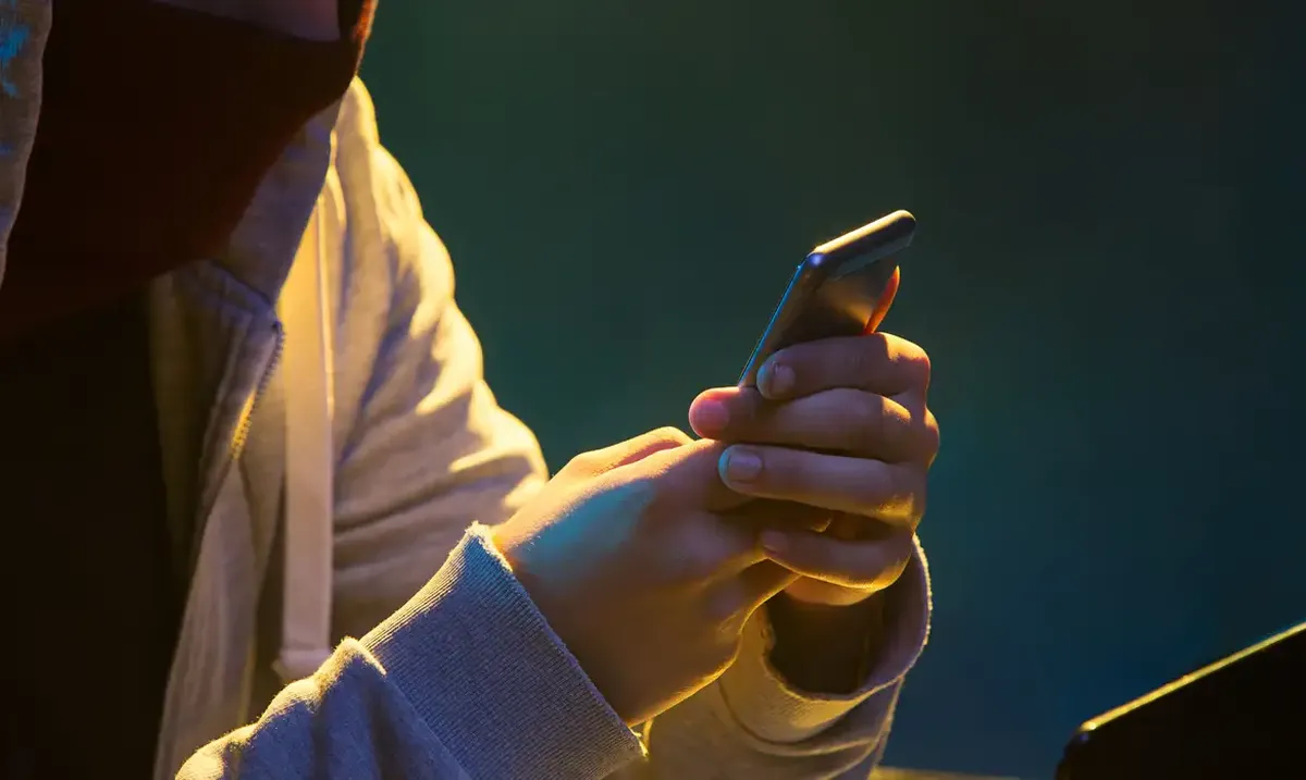 Pessoa usando um smartphone em um ambiente com iluminação suave, simbolizando a importância da segurança digital.