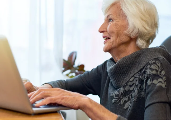 Idosa usando notebook para realizar solicitação online de isenção de IPTU.