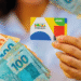 Cartão do Bolsa Família sendo exibido ao lado de cédulas de real