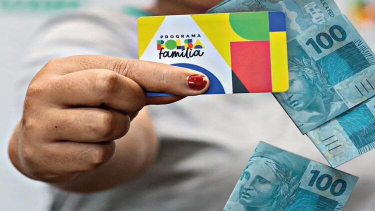 Pessoa segurando o cartão do Bolsa Família ao lado de notas de R$ 100 reais
