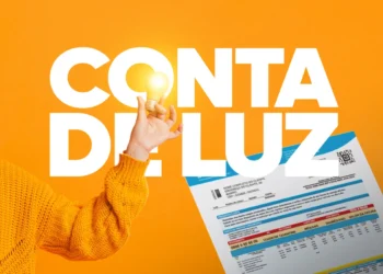 Pessoa segurando uma lâmpada com a conta de energia elétrica ao fundo, destacando a importância da Tarifa Social de Energia.