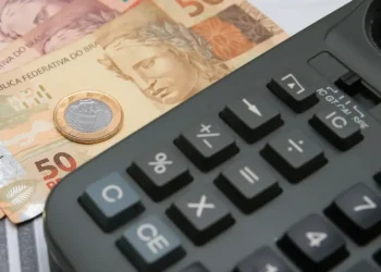 Notas de 50 reais e uma calculadora, simbolizando o uso do FGTS para o pagamento de dívidas.