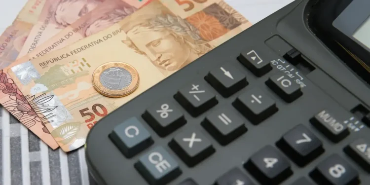Notas de 50 reais e uma calculadora, simbolizando o uso do FGTS para o pagamento de dívidas.