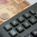 Notas de 50 reais e uma calculadora, simbolizando o uso do FGTS para o pagamento de dívidas.