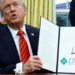 Donald Trump segurando um documento com sua assinatura, durante um discurso sobre uma investigação contra o Brasil e o Pix.