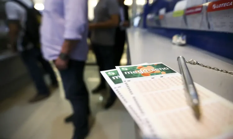 Volantes da Mega-Sena em balcão de lotérica com pessoas ao fundo