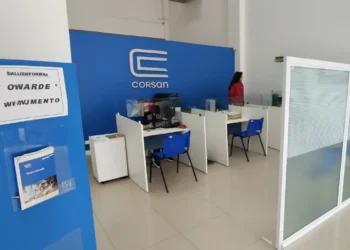Atendimento ao cliente na CORSAN em Passo Fundo, com cubículos e sinalização de espera."