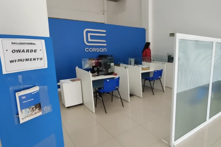 Atendimento ao cliente na CORSAN em Passo Fundo, com cubículos e sinalização de espera."