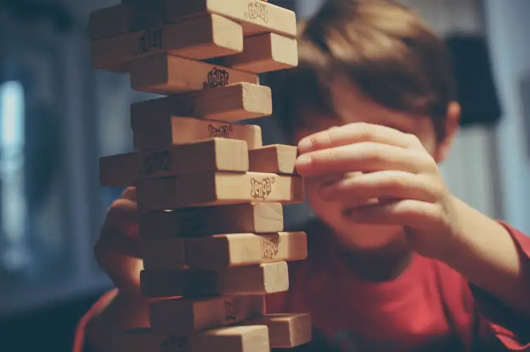 Criança brincando com peças de madeira do jogo Jenga