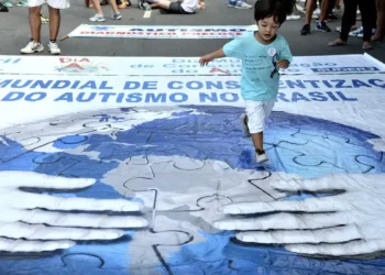 Criança caminha sobre banner de conscientização do autismo