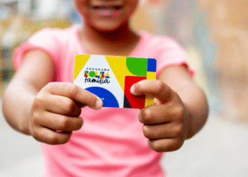 Criança segurando cartão do programa Bolsa Família 2025.