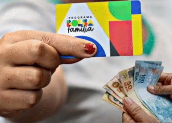 Cartão do Bolsa Família e dinheiro em notas de reais, relacionado à consulta sobre recebimento do benefício em agosto.