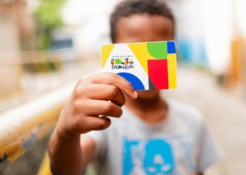 Criança segurando o cartão do Programa Bolsa Família