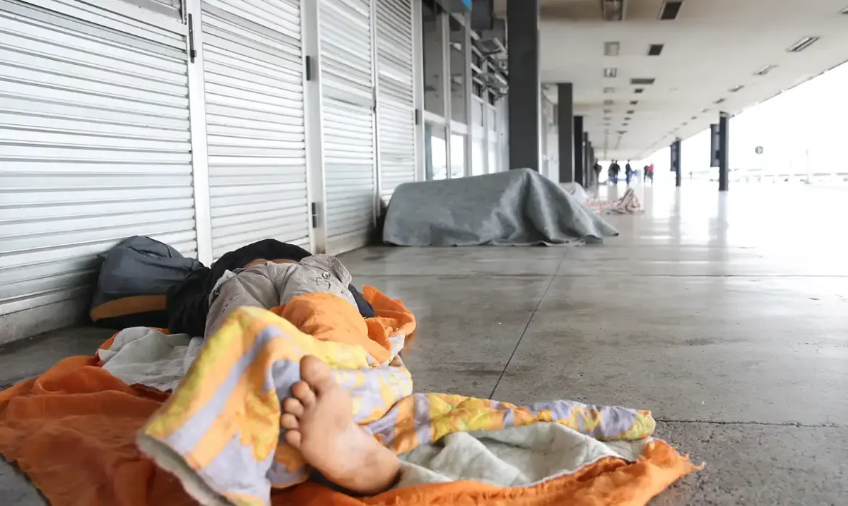 Pessoa em situação de rua em área pública, refletindo as desigualdades sociais abordadas nas mudanças do Bolsa Família 2025.