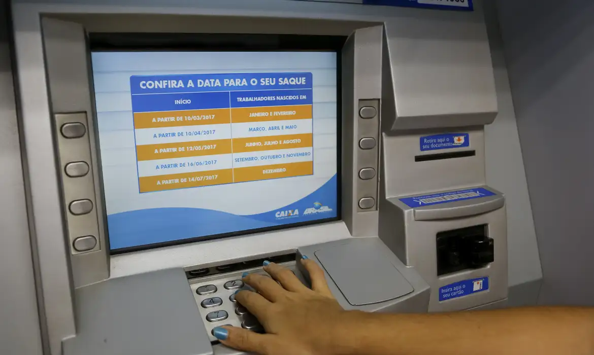 Pessoa utilizando caixa eletrônico da Caixa com calendário de saques na tela