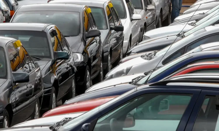 Carros populares estacionados em fila em pátio de revendedora