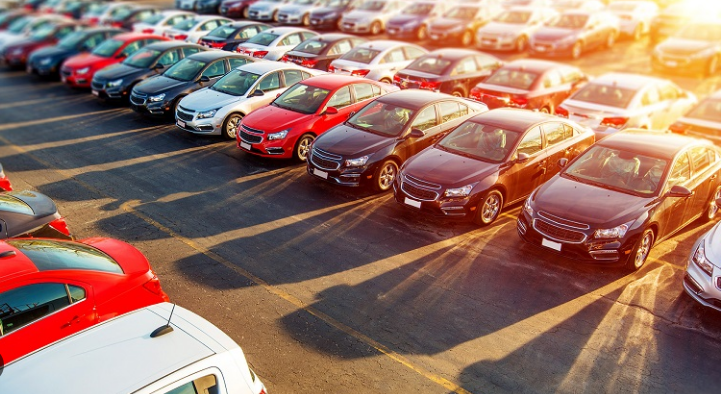 Linha de veículos populares de várias cores estacionados em um lote ao amanhecer, relacionada ao Programa carro sustentável.