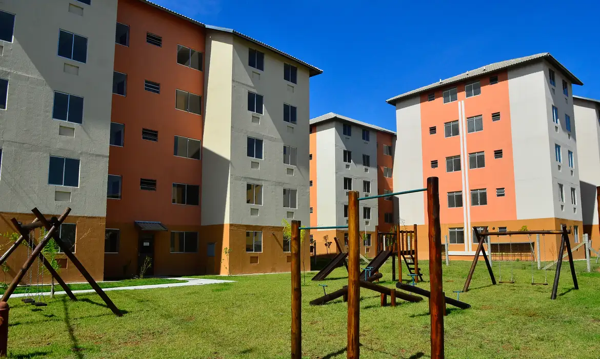 Prédios residenciais com área comum e playground ao ar livre.
