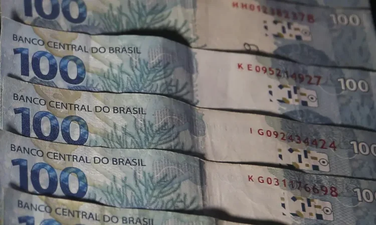 Cédulas de 100 reais empilhadas, representando o uso de dinheiro físico.
