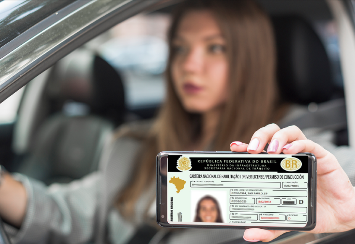 CNH Social 2025: Mulher segurando uma Carteira Nacional de Habilitação dentro de um carro.