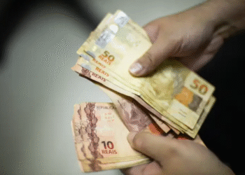 Notas de reais brasileiros, incluindo cédulas de 10 e 50 reais, empilhadas, representando dinheiro esquecido em bancos.