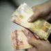 Notas de reais brasileiros, incluindo cédulas de 10 e 50 reais, empilhadas, representando dinheiro esquecido em bancos.