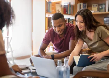 Estudantes colaborando em um projeto de computador, representando o processo de acessar informações importantes para o Encceja 2025.