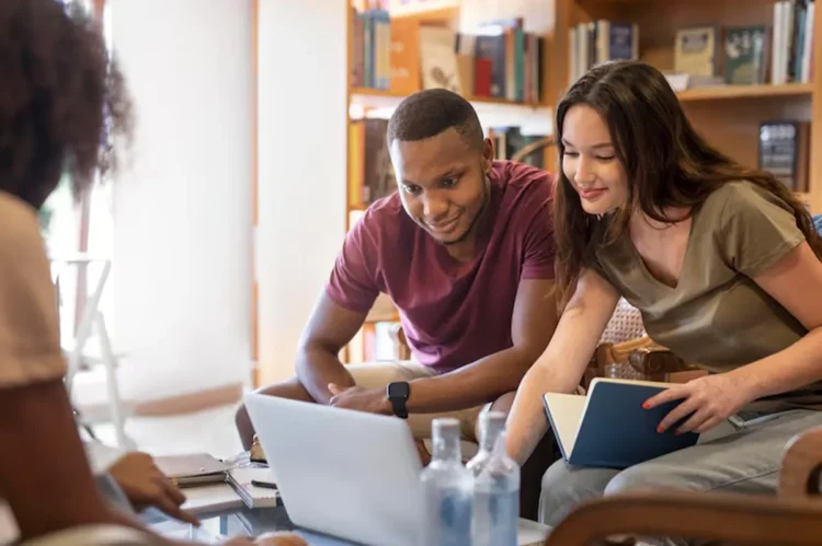 Estudantes colaborando em um projeto de computador, representando o processo de acessar informações importantes para o Encceja 2025.