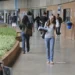 Estudantes circulando por corredor de instituição de ensino com mochilas e materiais
