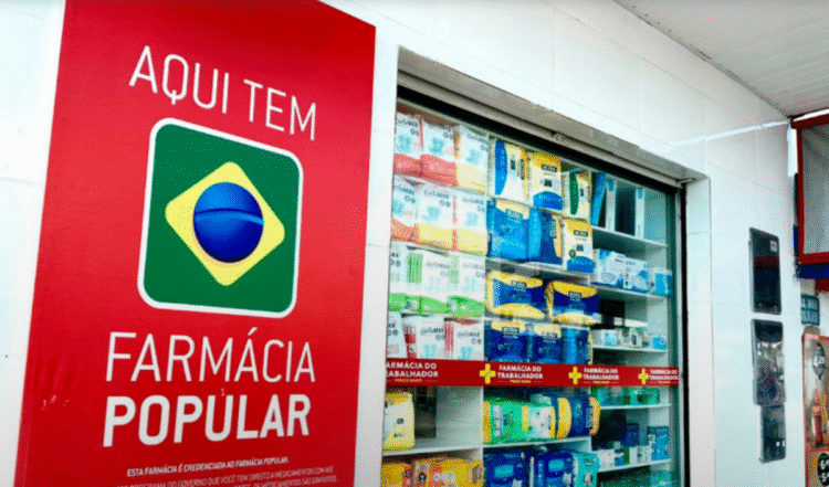 Fachada de uma Farmácia Popular com prateleiras de medicamentos e o logotipo do programa brasileiro.