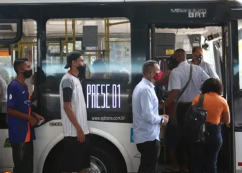 Passageiros usando máscara embarcam em ônibus do transporte público em São Paulo