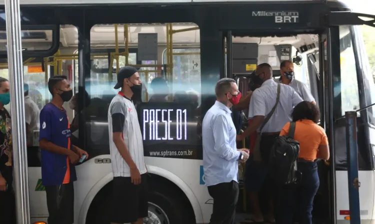 Passageiros usando máscara embarcam em ônibus do transporte público em São Paulo