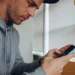 Homem usando celular com expressão desconfiada, alerta para possíveis golpes