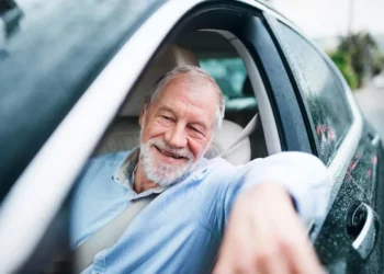 Idoso sorrindo enquanto dirige, ilustrando benefícios de desconto para a compra de carros novos