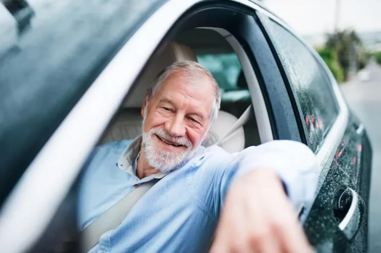Idoso sorrindo enquanto dirige, ilustrando benefícios de desconto para a compra de carros novos