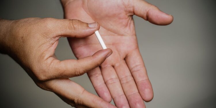 Implante contraceptivo sendo exibido na palma da mão