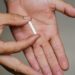 Implante contraceptivo sendo exibido na palma da mão