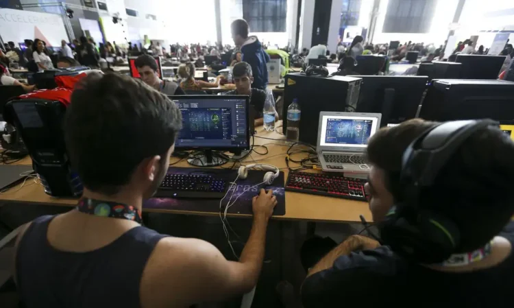 Jovens participam de atividade digital em ambiente colaborativo com computadores