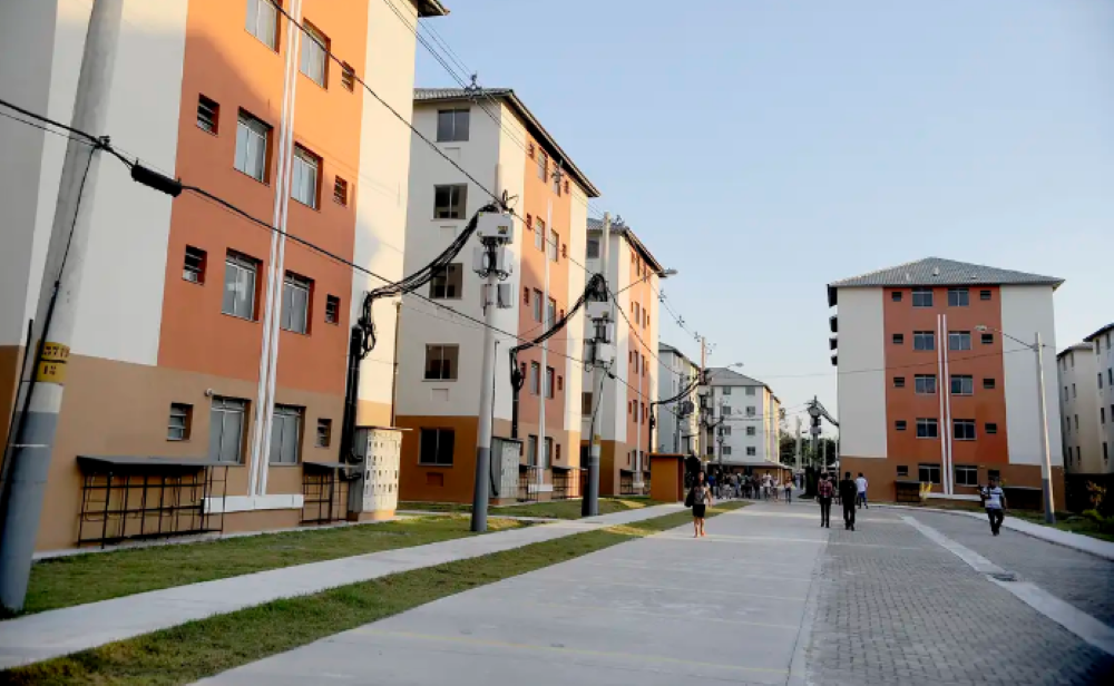 Conjunto habitacional do programa Minha Casa, Minha Vida com moradores caminhando pelas ruas.
