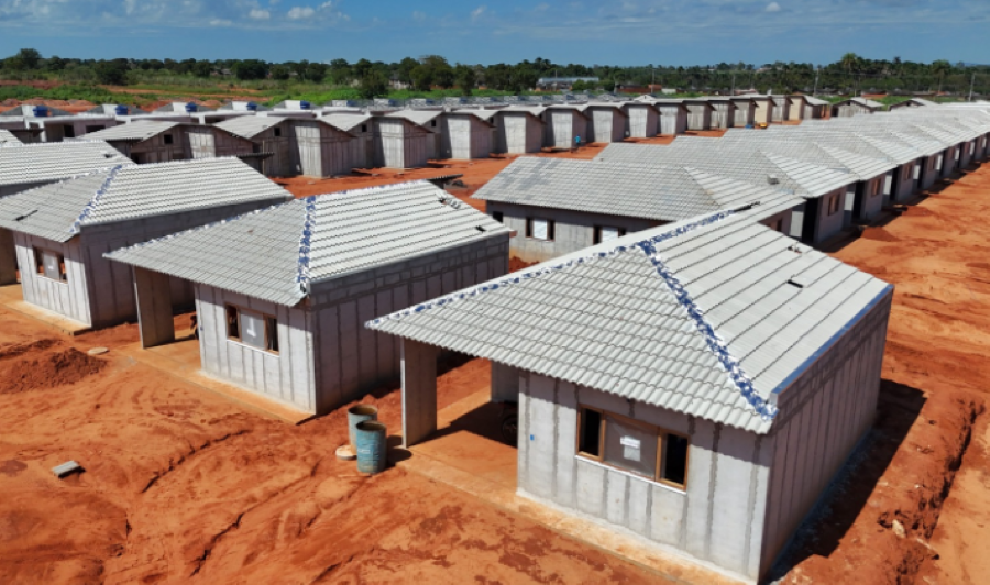 Imagem de casas do programa Minha Casa Minha Vida em construção em terreno de terra vermelha.