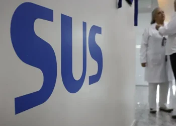 Profissionais conversando em unidade de saúde com o logo do SUS em destaque