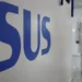 Profissionais conversando em unidade de saúde com o logo do SUS em destaque