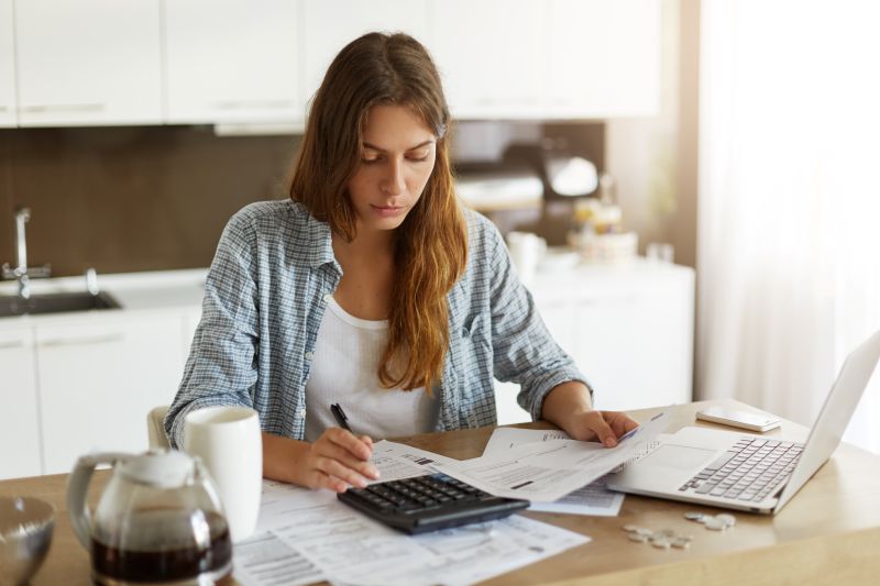 Mulher jovem calculando despesas domésticas na cozinha