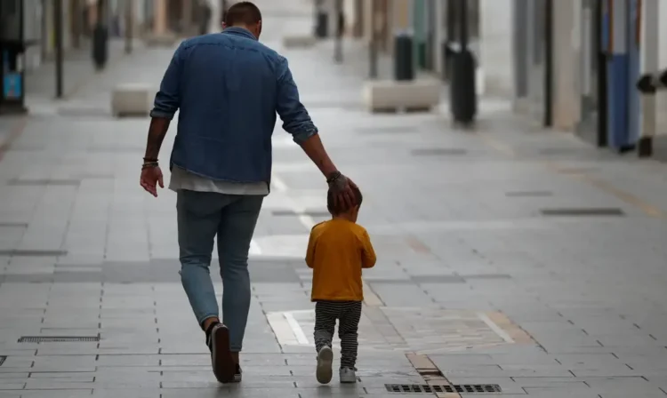 Pai e filho caminhando juntos em uma rua tranquila, simbolizando o apoio e a união familiar no mutirão gratuito de testes de DNA.