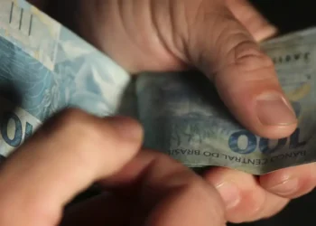 Pessoa contando notas de cem reais