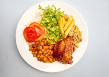 Prato com arroz, feijão, frango assado, salada e batata, simbolizando refeição garantida pelo cartão-alimentação