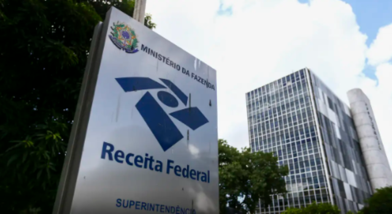 Placa da Receita Federal com prédio ao fundo, representando as novas regras do CNPJ que incluem letras e números.
