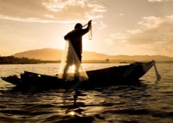 Pescador recolhendo rede ao pôr do sol durante o período de defeso
